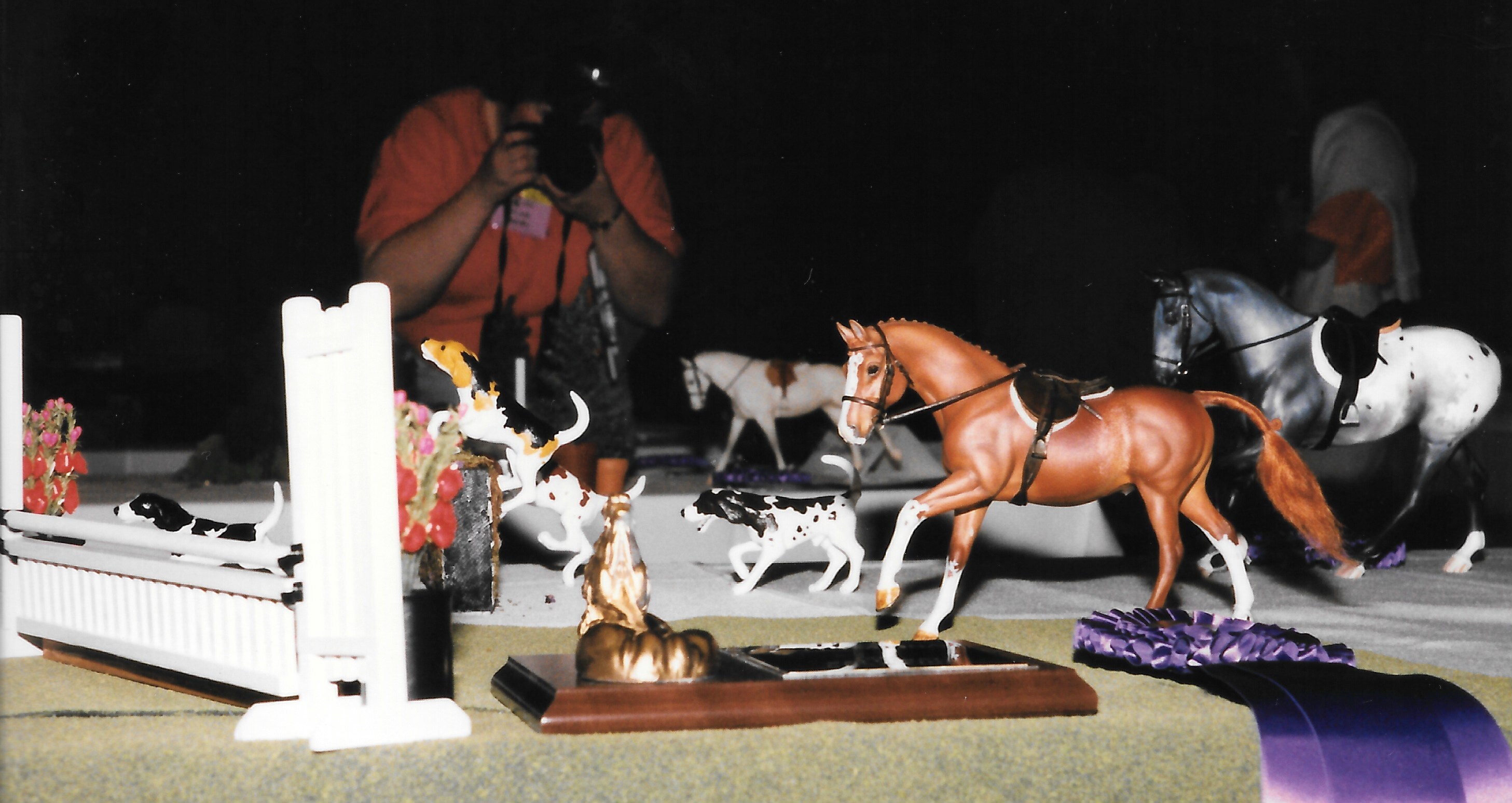 Chestnut pony cantering towards a jump on the table at NAN 1996 with his national championship plaque and rosette