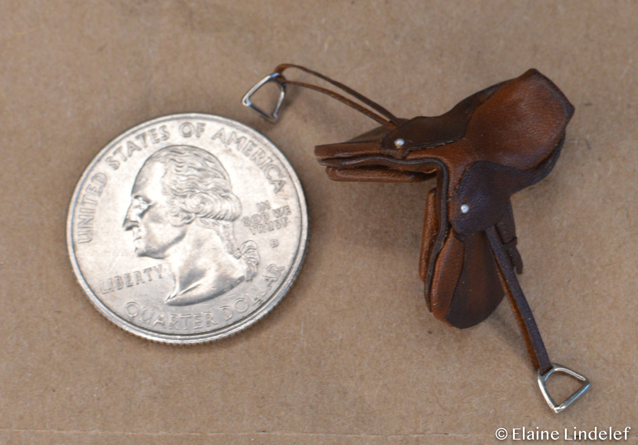 Stablemate sized english saddle made by Elaine Lindelef, next to a quarter for scale.